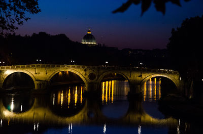 Illuminated bridge over river against sky at night