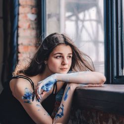 Young woman looking through window