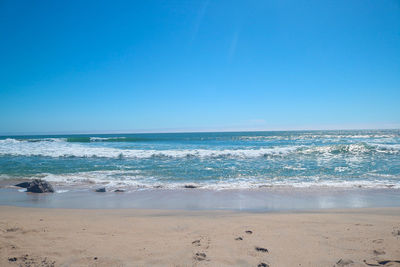 Scenic view of beach against clear blue sky