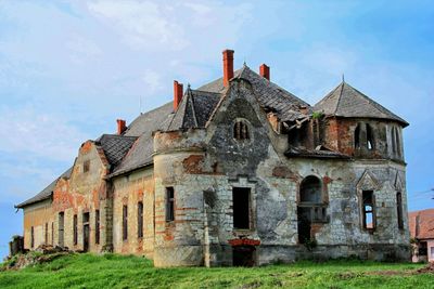 Abandoned building against cloudy sky