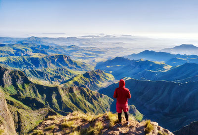 Rear view of man standing on mountain against sky