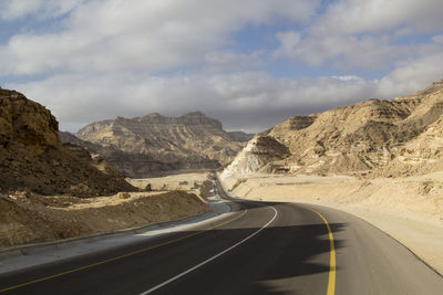 Scenic view of mountain road against cloudy sky