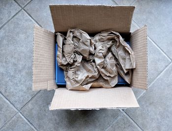 Directly above shot of crumpled paper in cardboard box on footpath