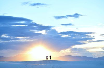 Silhouette people standing on snow covered mountain against sky