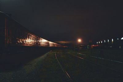 Train on illuminated bridge against sky at night