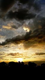 Silhouette landscape against dramatic sky during sunset