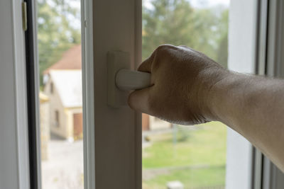 Close-up of man hand by window at home