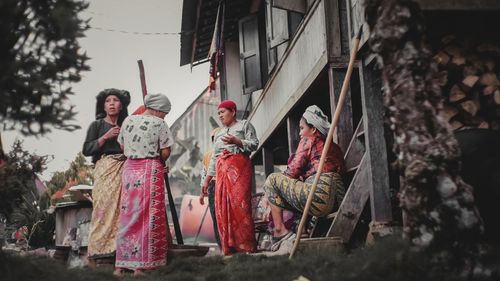 Full length of friends standing against built structure