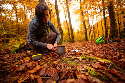 Portrait of young man using mobile phone while standing in forest