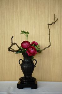 Close-up of roses in vase on table against wall