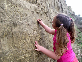 Rear view of girl drawing on rock