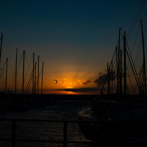 Silhouette sailboats moored on sea against sky during sunset