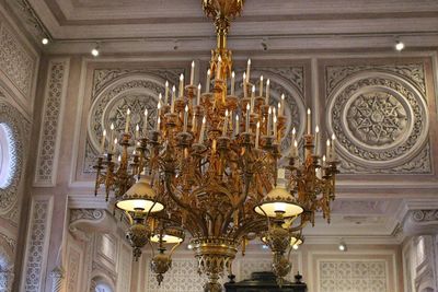 Low angle view of illuminated chandelier hanging on ceiling of building