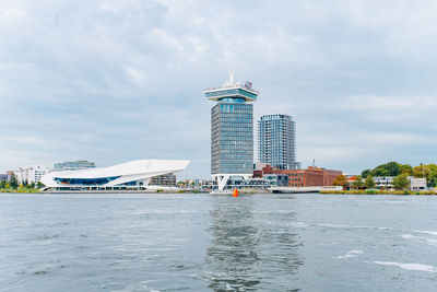 Sea by buildings against sky in city