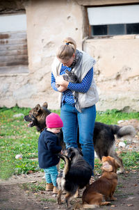 Happy family-mother with  children hugging and feeds pets dogs, cats and goats in countryside farm