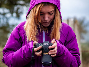 Portrait of woman holding purple camera