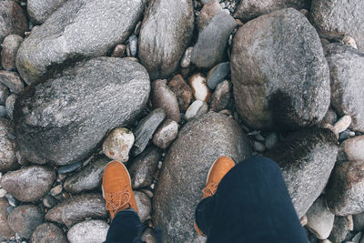 One person walks above rocks wearing boots at daytime