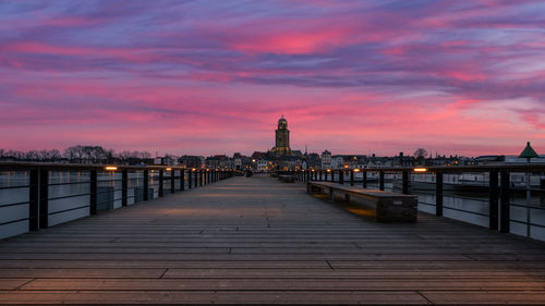 View of bridge over river against buildings at sunset