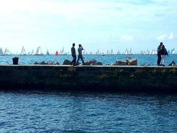 Men standing on sea against sky