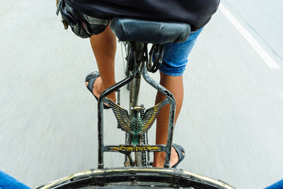 Low section of man riding bicycle on road