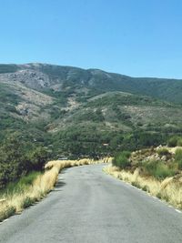 Road amidst landscape against clear blue sky