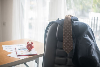 Close-up of necktie and blazer on chair in office