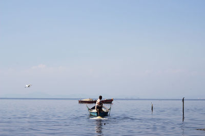 Fisherman fishing in sea against blue sky