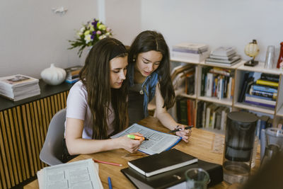 Young female friends studying together at table