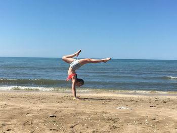 Full length of woman walking on beach against clear sky