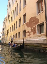 People on boat in canal along buildings