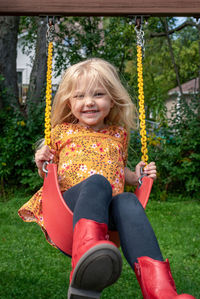 Portrait of a girl sitting on swing at playground