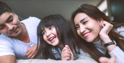 Close-up of smiling family lying on bed at home