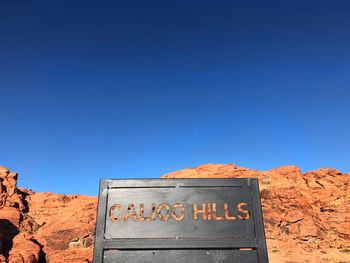 Text on rock against clear blue sky