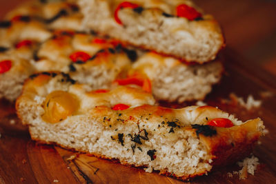 
homemade italian focaccia slices, with tomato and olive oil on a rustic wooden background.