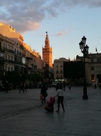 People on street by buildings against sky in city