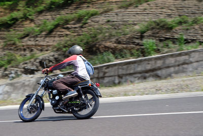 Rear view of man riding motorcycle on road