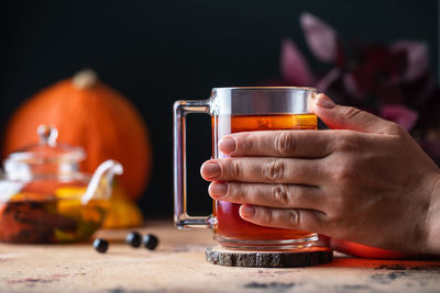 A woman in a sweater holds a mug of hot tea with lemon. autumn time.