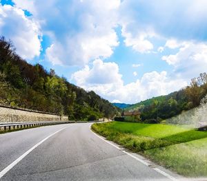 Empty road by trees against sky