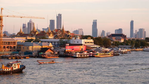 Boats sailing in river with city in background