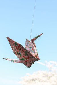 Low angle view of paper crane against clear blue sky