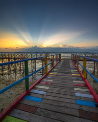 Pier over sea against sky during sunset