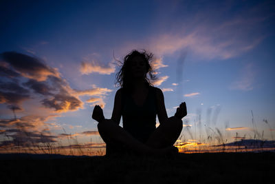 Silhouette woman with arms raised against sky during sunset