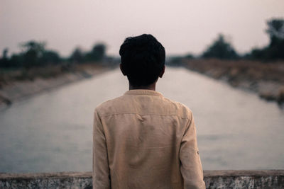 Rear view of man standing on road against sky