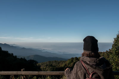 Rear view of man looking at mountains against sky