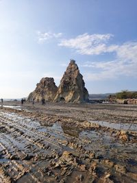 Rock formations on beach against sky