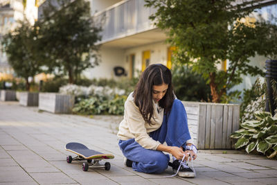 Girl skateboarder tying shoes