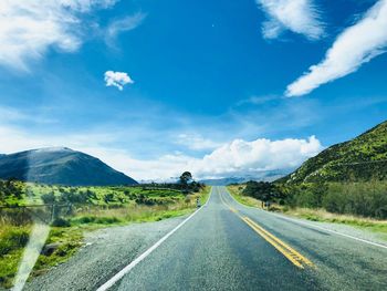 Road leading towards mountains against sky