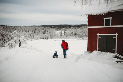 Rear view of people walking on snow covered landscape against sky