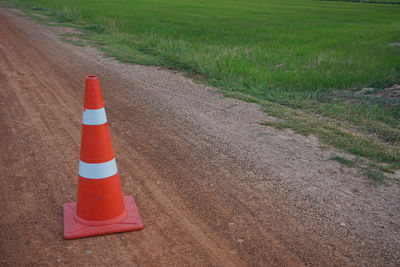 Arrow sign on road amidst field