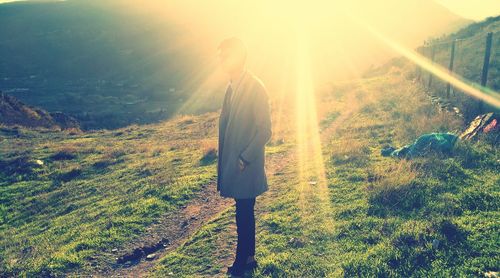 Rear view of man walking on landscape against sky